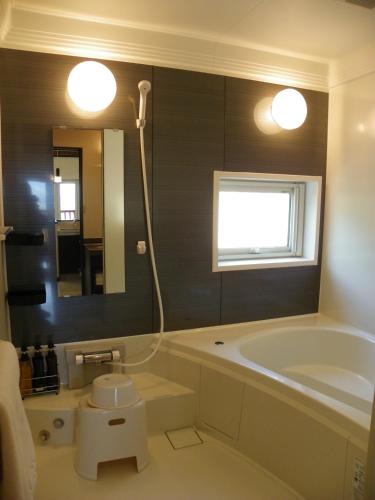 a bathroom with a tub and a sink and a mirror at Chalet Fuyuri in Furano
