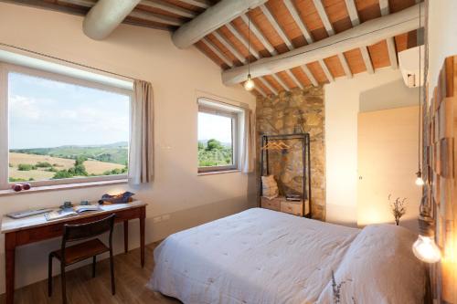 a bedroom with a bed and a desk and a window at Casale Sterpeti in Magliano in Toscana