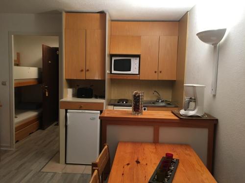 une petite cuisine avec une table et un micro-ondes dans l'établissement Studio Cabine Les Balcons du Soleil, à Font-Romeu-Odeillo-Via