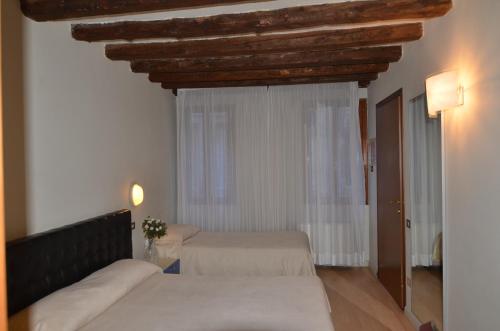 a bedroom with two beds and a large window at Piccolo Tiepolo in Venice