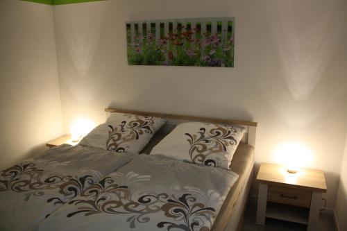ピルナにあるFerienwohnung am Riesenfussのベッドルーム1室(ランプ2つ、壁に絵画付)