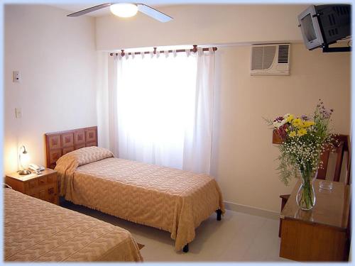 a bedroom with two beds and a window with a vase of flowers at Hotel Lihuel Calel in Santa Rosa