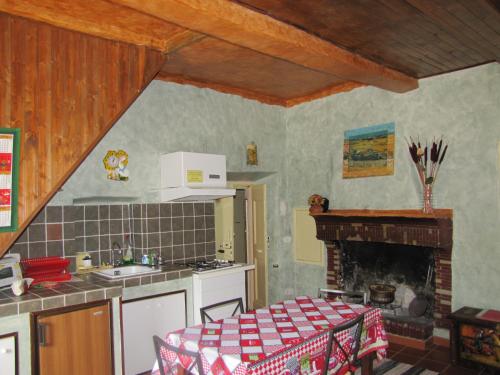 a kitchen with a table and a stove and a fireplace at Maison Dina in Collepardo