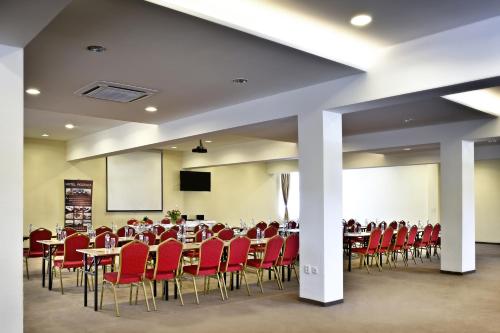 a conference room with red chairs and tables and a screen at Hotel Rozálka in Pezinok