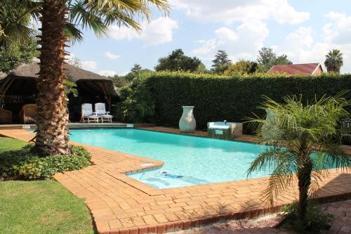 a swimming pool in a yard with a palm tree at Fin and Feather Guest Lodge in Boksburg