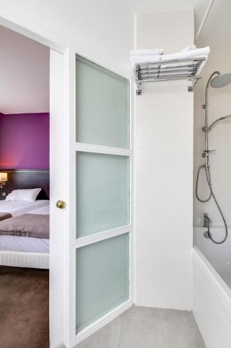 a bathroom with a glass door leading to a bedroom at Hôtel Le Mondon Metz in Metz