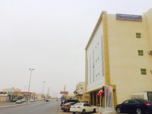 a building on the side of a street with cars parked at Qsr Al Balsem Aparthotel in Unayzah
