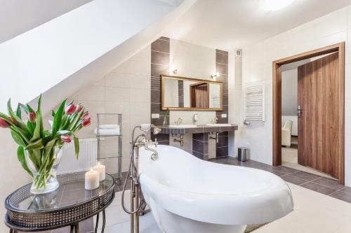 a bathroom with a white tub and a glass table at Hotel Modrzewiowy Dwór in Gliwice