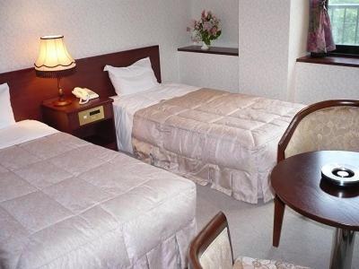 a hotel room with two beds and a table at Gokayama Onsen Akaokan in Nanto