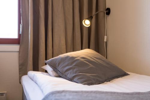 a bed with a pillow and a lamp next to a window at Hotelli Uninen Tampere in Tampere