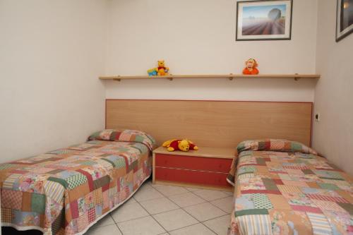 カヴァッリーノ・トレポルティにあるVillini Joker ai Frassiniのベッドルーム1室(ベッド2台、壁に棚付)