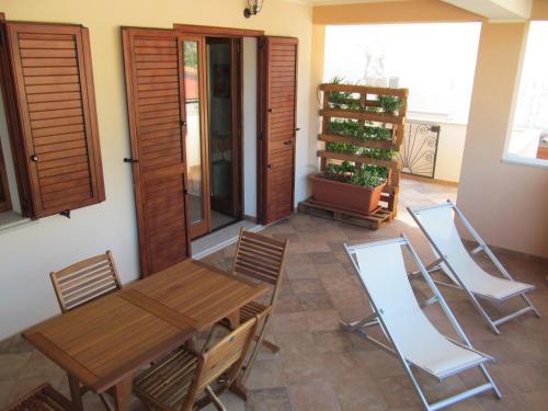 une salle à manger avec une table en bois et des chaises blanches dans l'établissement Appartamento Mirto, à Buggerru