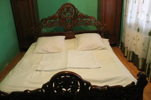 a bed with a wooden headboard and white sheets at Villa Jakos Paradise in Batumi