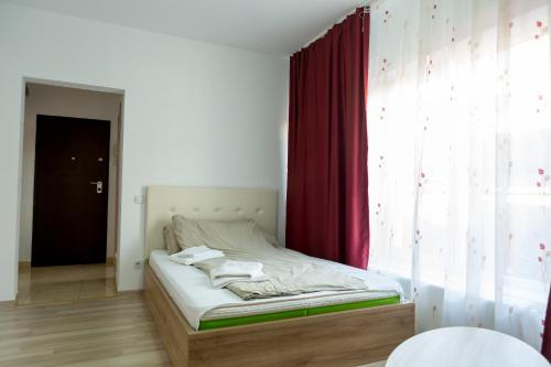 Cama en habitación con cortina roja en Garsoniere Dinu, en Bucarest