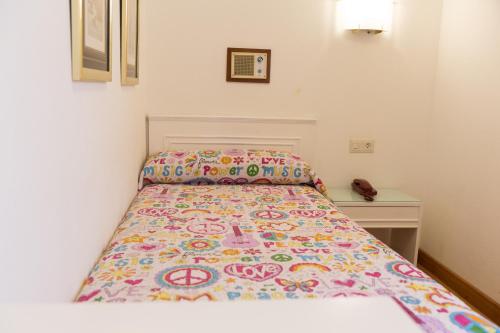 a small bedroom with a bed with a colorful bedspread at Rey Fernando in Santiago de Compostela
