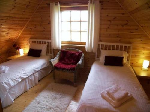 1 dormitorio con 2 camas, silla y ventana en Benview Lodges, en Kepculloch