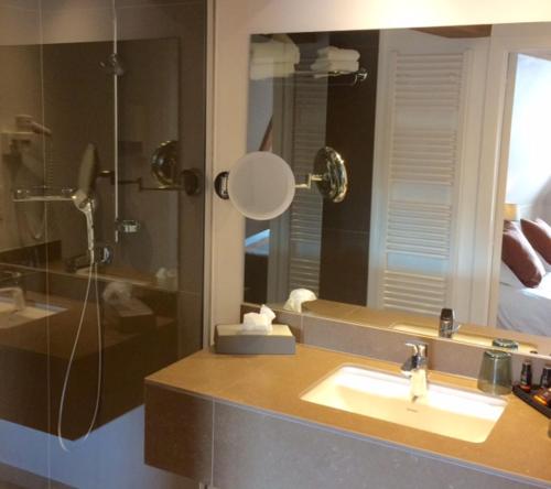 een badkamer met een wastafel, een douche en een spiegel bij Hotel Ter Duinen in Brugge