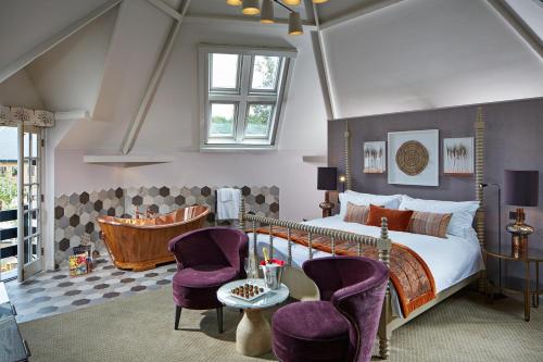 a bedroom with a bed and two purple chairs at Pennyhill Park Hotel and Spa in Bagshot