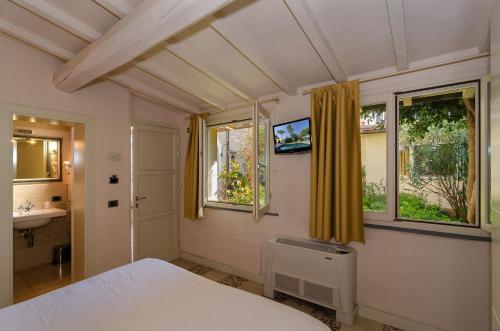 a bedroom with a bed and a sink and windows at Hotel Novecento in Pisa