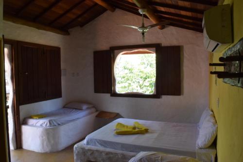 two beds in a room with a window at Pousada Cavallitos d'Amar in Ilha de Boipeba