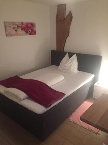 a bed with white sheets and a red blanket on it at Pension Sunnseitn - Gasthof - Café - Weinkeller in Haslach an der Mühl