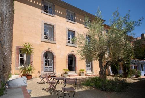a building with a table and chairs in front of it at La Maison Vieille Maison d'Hôtes & Gîtes in Carcassonne
