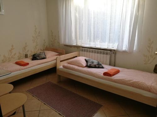 two beds in a room with a window at Dom Mysliwski in Kobyłka