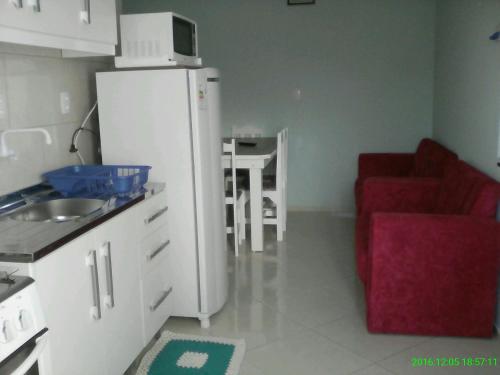 a kitchen with a white refrigerator and a red couch at Apartamento Favreto in Marechal Luz