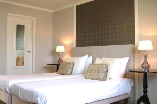 a bedroom with a large white bed with two lamps at Hotel Brull in Mechelen