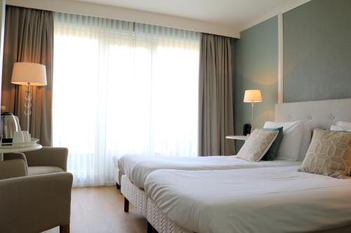 a hotel room with two beds and a window at Hotel Brull in Mechelen