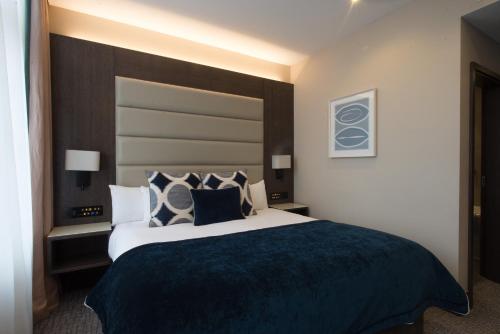 a bedroom with a large bed with blue blanket and pillows at The Kings Head Hotel in London