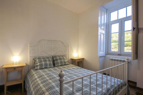 a bedroom with a bed with two tables and two windows at Mountain House/ Serra da Estrela in Penhas da Saúde