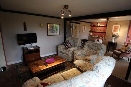 a living room with two couches and a tv at Wishing Well Cottage in Wilmington