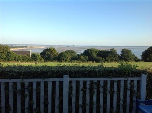 een wit hek met uitzicht op een veld en de oceaan bij Les Hermelles in Champeaux