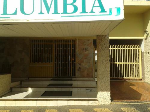 una puerta delantera de un edificio con un cartel en Hotel Columbia Palace en Pirassununga