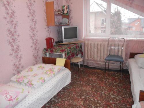 a room with a bed and a desk with a television at Guest House Raisa in Brest