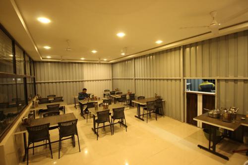 un restaurante con mesas y sillas y un hombre de fondo en Hotel Yog Palace Newly Renovated 2023, en Shirdi