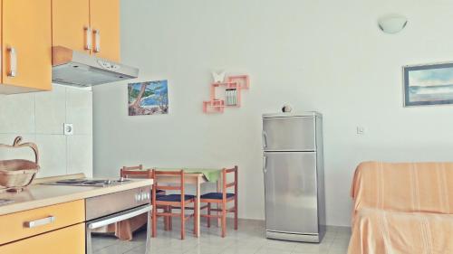 a kitchen with a refrigerator and a table with chairs at Luka Kokić Apartments in Podgora
