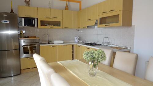 a kitchen with a table with a vase of flowers on it at Apartments Braco in Seget Vranjica