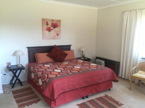 Un dormitorio con una cama con un edredón rojo. en Hawley House, en Underberg