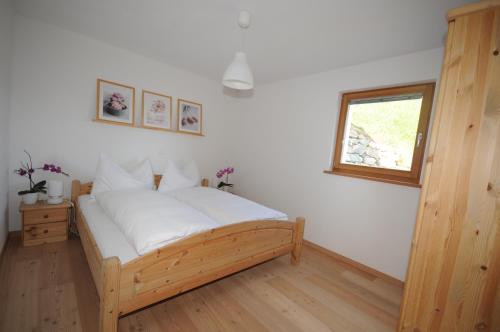 1 dormitorio con cama de madera y ventana en Ferienwohnung Caviezel en Tschlin 