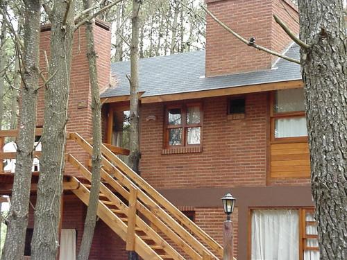 a red brick house with a wooden staircase in front at Cabañas El Ocio in Mar de las Pampas