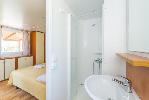 a bathroom with a sink and a bed at Mobile Homes Plava Laguna in Pakoštane