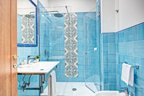a blue tiled bathroom with a sink and a shower at Oleum in Massa Lubrense