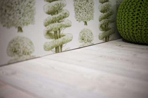 a table with a green vase and a wall with plants at Dimora Al Bivacco in Pieve di Cadore