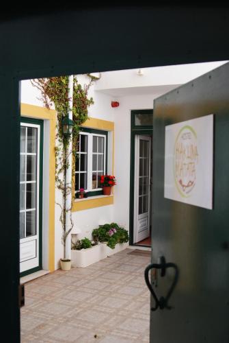 an open door of a building with plants and flowers at Hakuna Matata Hostel in Zambujeira do Mar
