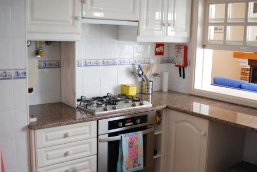a kitchen with white cabinets and a stove top oven at Hakuna Matata Hostel in Zambujeira do Mar