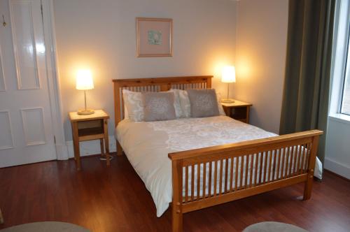 ダヌーンにあるSebright Holiday Apartmentのベッドルーム1室(木製ベッド1台、ランプ2つ、テーブル2台付)