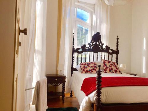 a bedroom with a bed with a red blanket and a window at A Vianesa - Guest House in Viana do Castelo