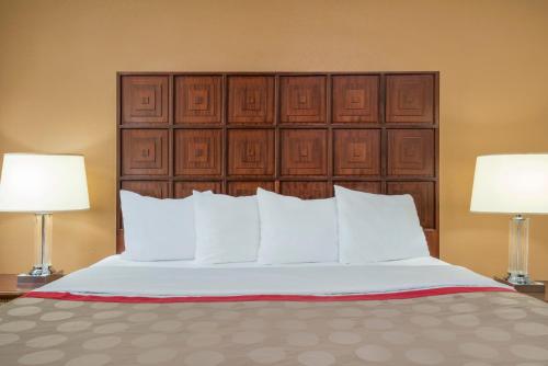 a bed with white pillows and two lamps at Ramada by Wyndham Columbus North in Westerville